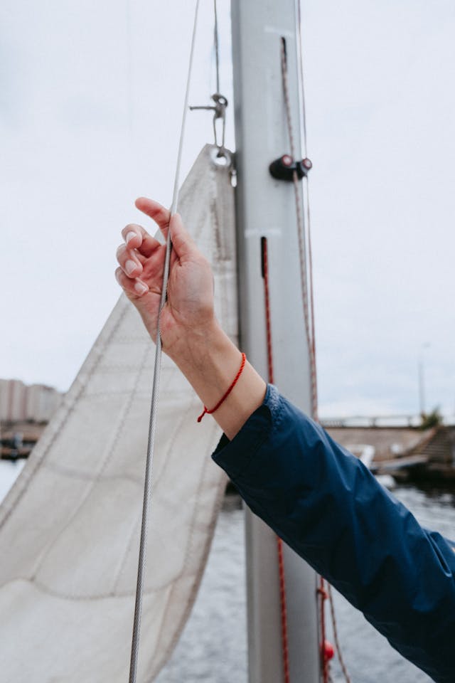 A determined sailor actively hoisting a sail, embodying the proactive strategies of influence and negotiation—putting skills into action as taught in Playbook 2.